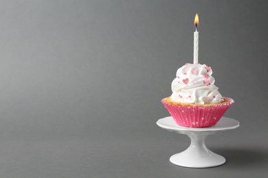 Delicious cupcake with candle on grey background. Space for text