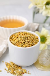 Photo of Fresh bee pollen granules and dipper with honey on white table, closeup