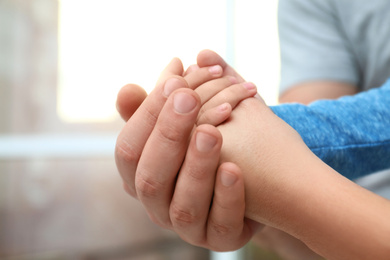 Happy family holding hands indoors, closeup view