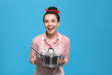 Photo of Housewife with pan on light blue background