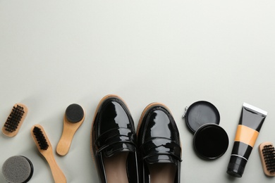 Flat lay composition with shoe care accessories and footwear on light grey background. Space for text