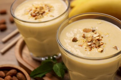 Tasty banana smoothie with almond on wooden table, closeup. Space for text