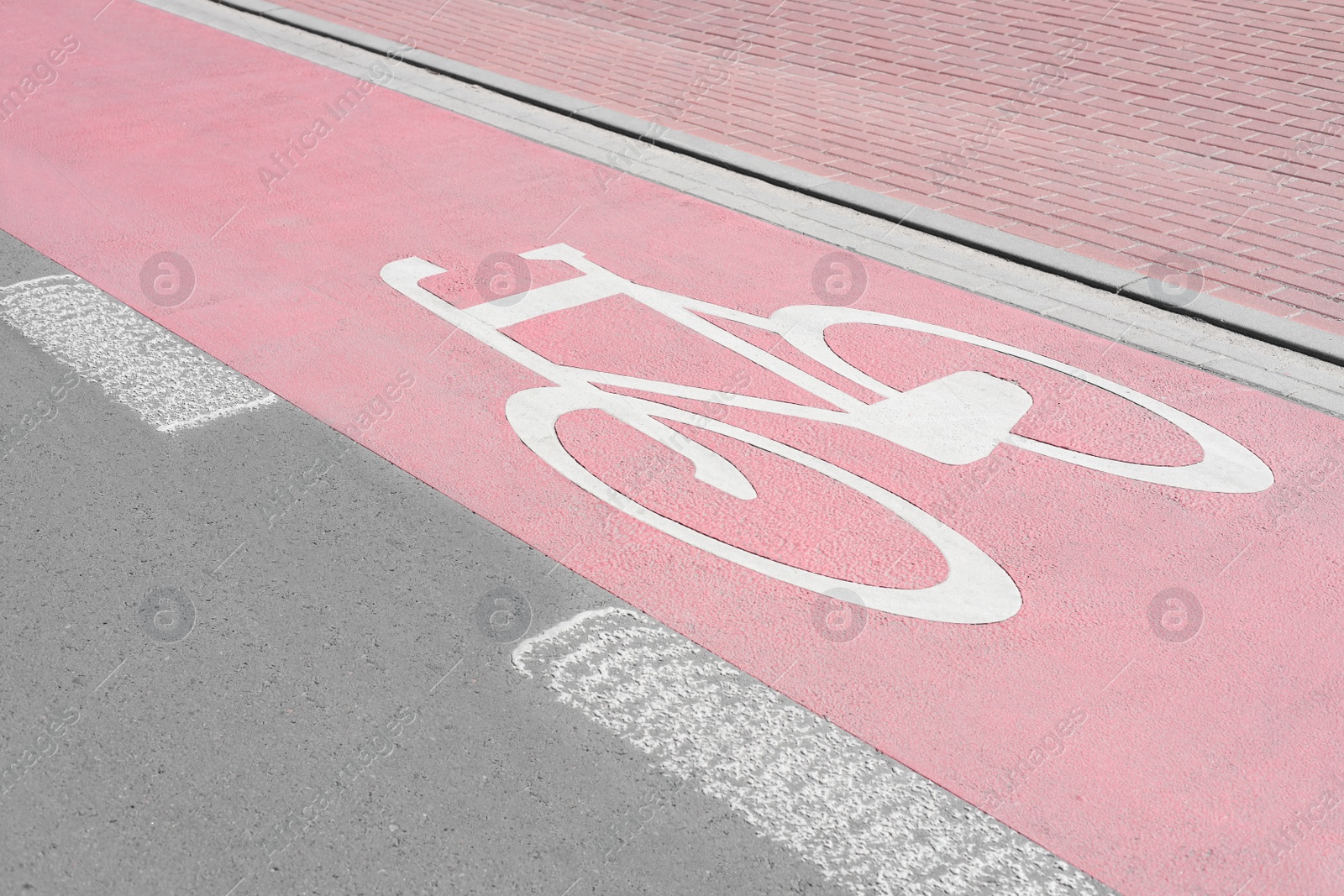 Photo of Red bike lane with painted white bicycle sign on sunny day