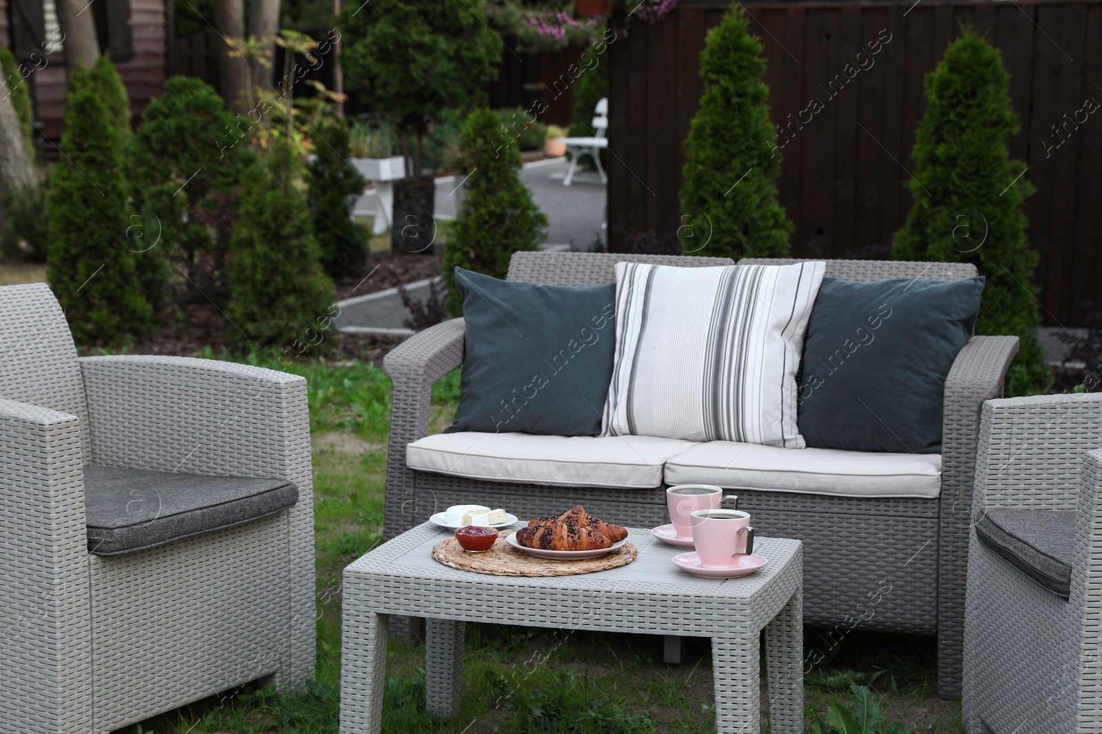 Photo of Outdoor breakfast with tea and croissants on rattan table in garden