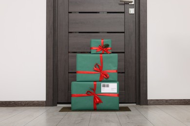 Photo of Christmas gift boxes on floor near door. Sending present by mail