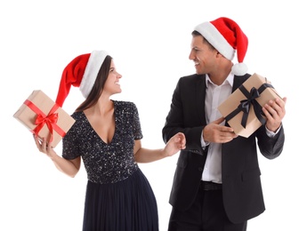 Photo of Beautiful happy couple in Santa hats holding Christmas gifts on white background