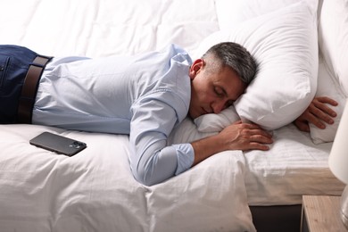 Photo of Businessman in office clothes sleeping on bed indoors