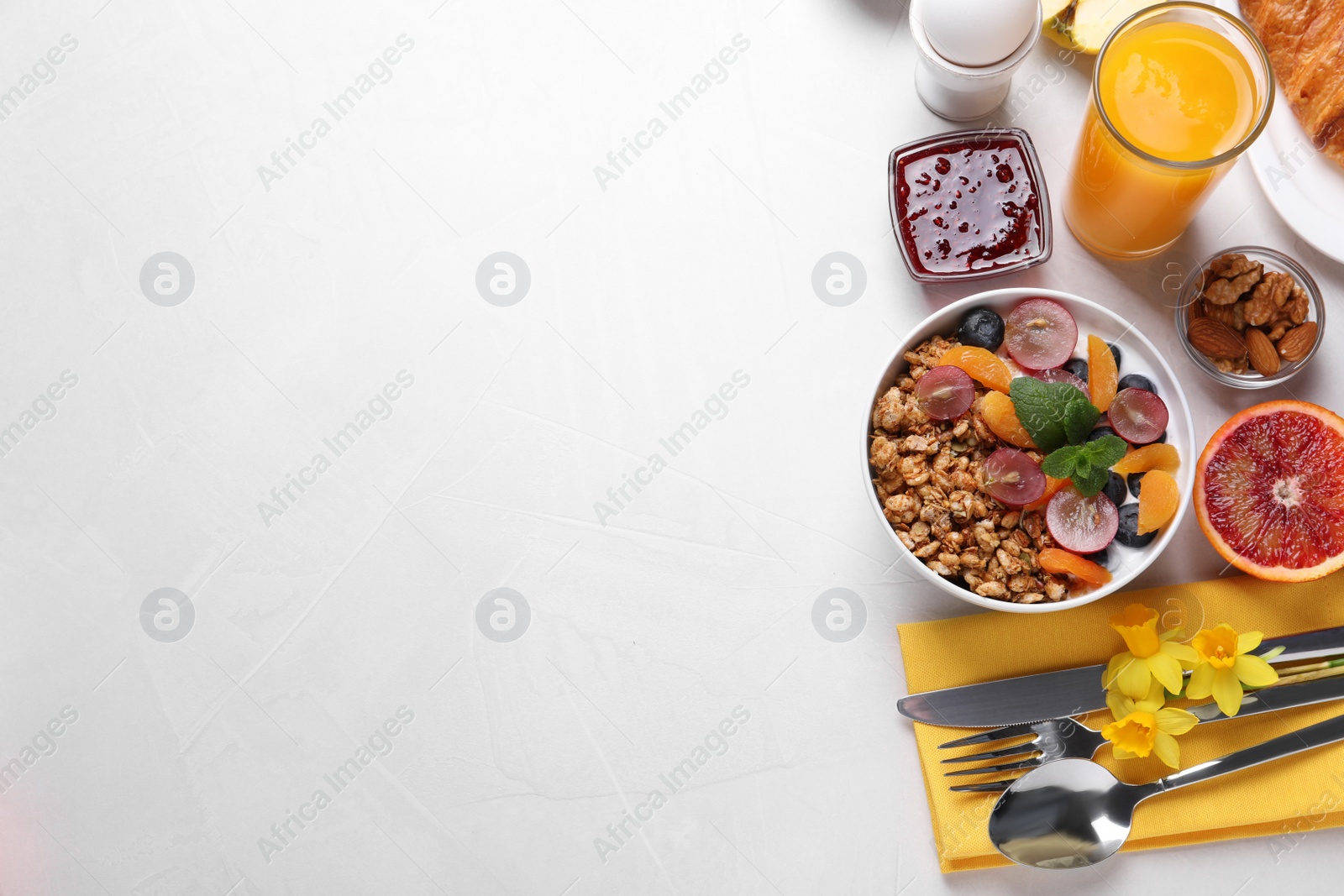 Photo of Delicious breakfast with granola on white table, flat lay. Space for text