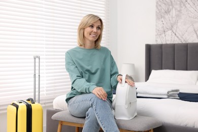 Photo of Smiling guest with backpack and suitcase in stylish hotel room