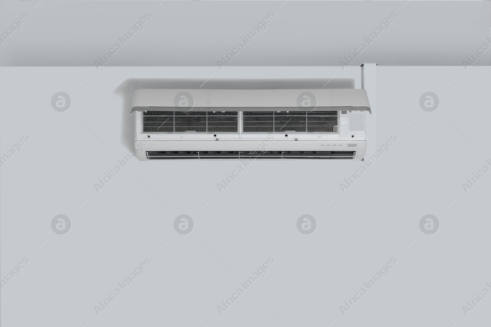 Photo of Modern air conditioner on white wall indoors. Space for text