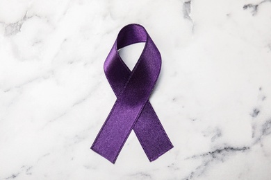 Purple ribbon on white marble background, top view. Domestic violence awareness