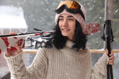 Young woman with skis wearing winter sport clothes and goggles outdoors