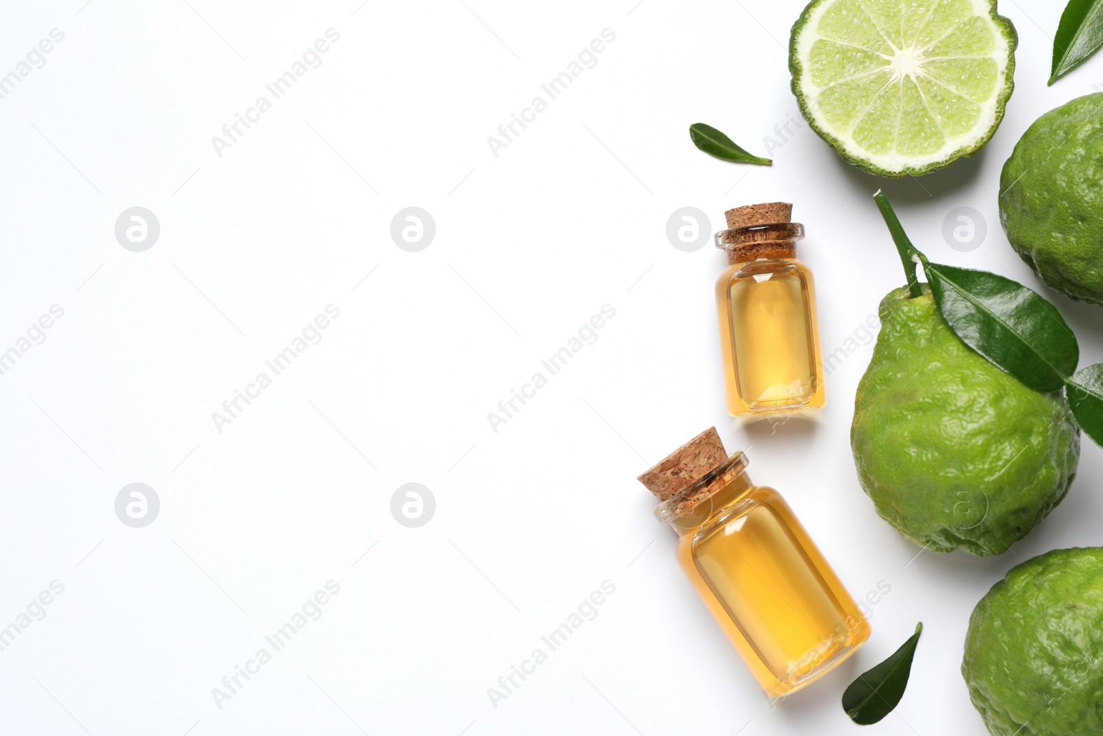 Photo of Glass bottles of bergamot essential oil and fresh fruits on white background, flat lay. Space for text