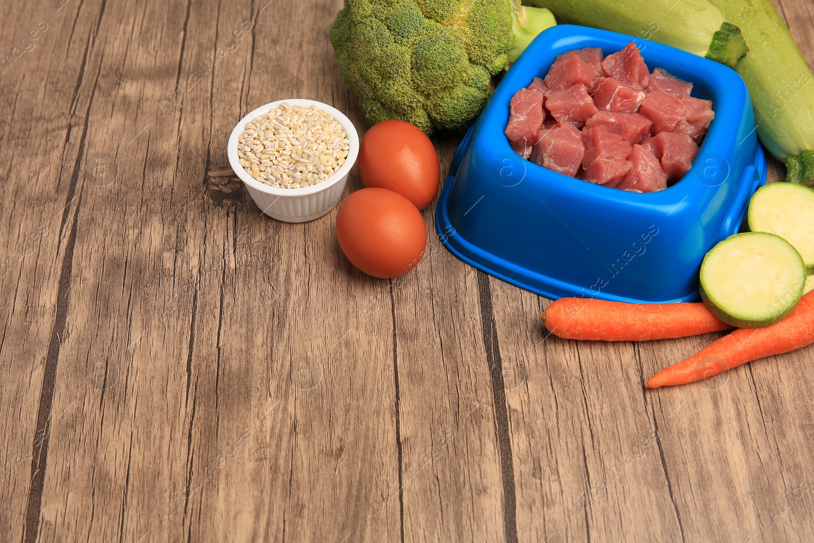 Photo of Raw meat in bowl and healthy products for pet on wooden background. Space for text