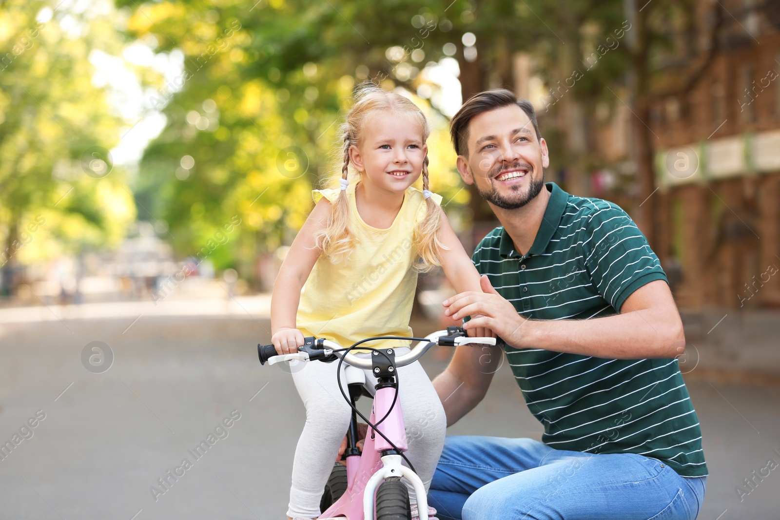 Photo of Father teaching daughter to ride bicycle on street