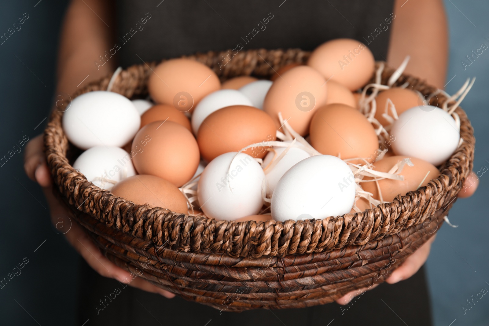 Photo of Woman with basket full of raw chicken eggs, closeup