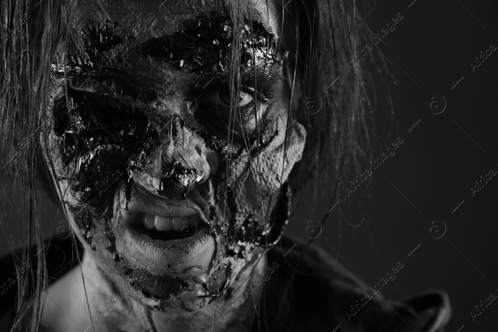 Photo of Scary zombie on dark background, black and white effect. Halloween monster