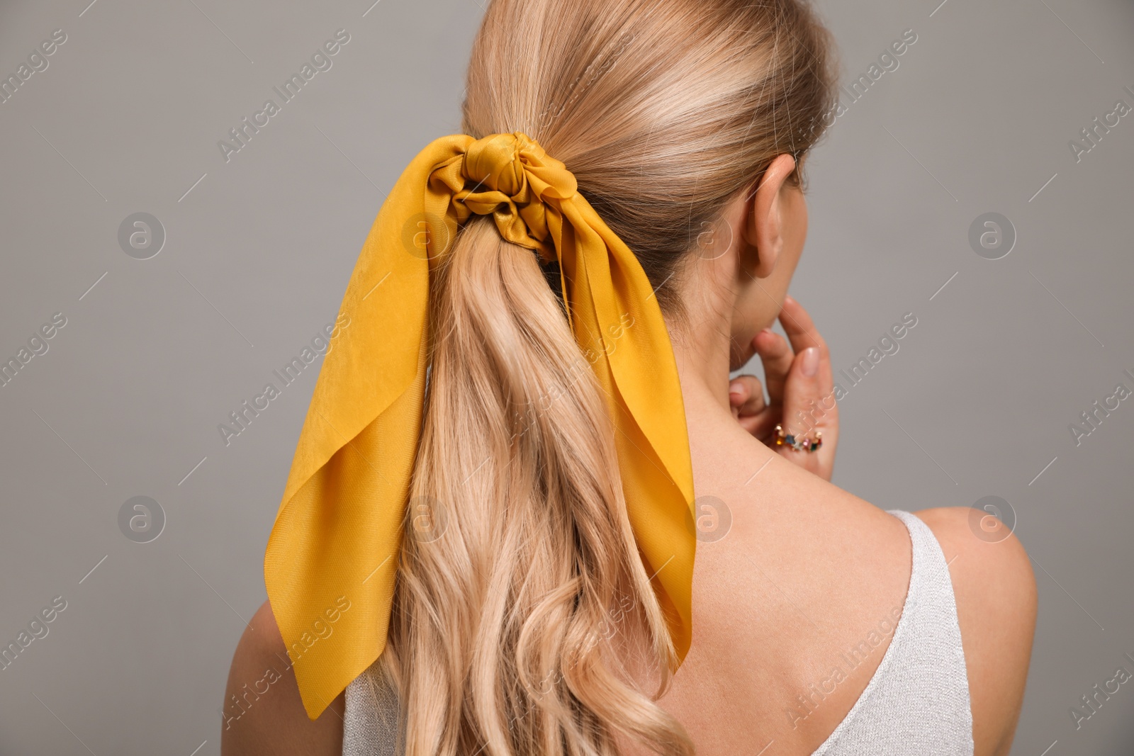 Photo of Young woman with stylish bandana on grey background, back view