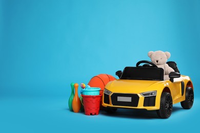 Photo of Child's electric car with other toys on light blue background. Space for text