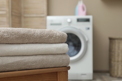 Photo of Clean folded towels on table in modern laundry room, space for text