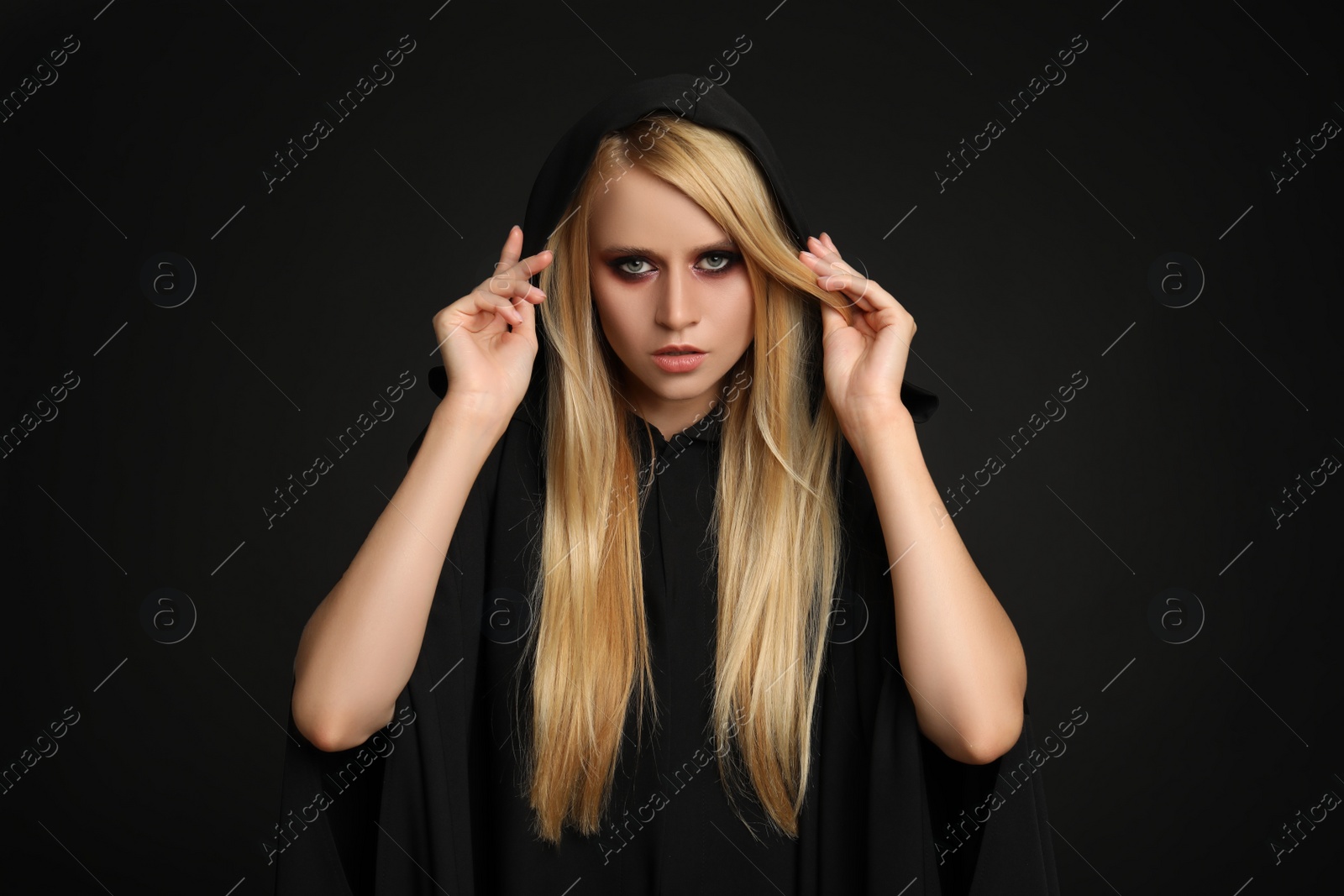 Photo of Witch in black mantle on dark background. Scary fantasy character