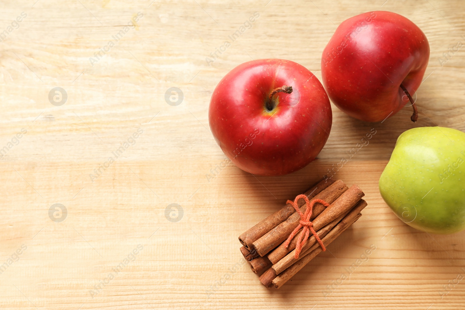 Photo of Fresh apples and cinnamon sticks on wooden table