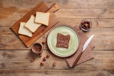 Toast with tasty nut butter and hazelnuts on wooden table, flat lay