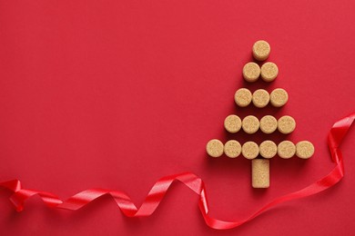 Christmas tree made of wine corks and ribbon on red background, flat lay. Space for text