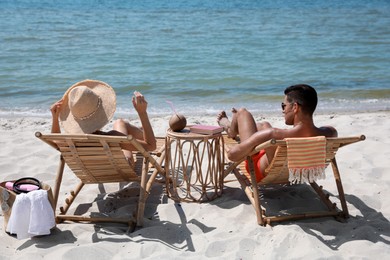 Photo of Couple resting in wooden sunbeds on tropical beach