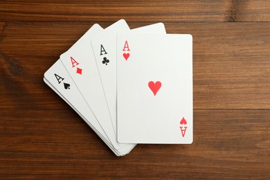 Photo of Four aces playing cards on wooden table, flat lay