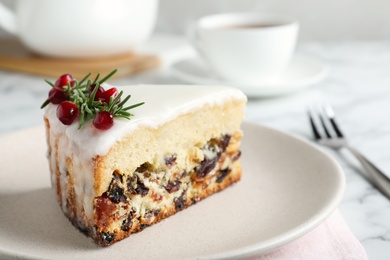 Slice of traditional Christmas cake decorated with rosemary and pomegranate seeds on table, closeup