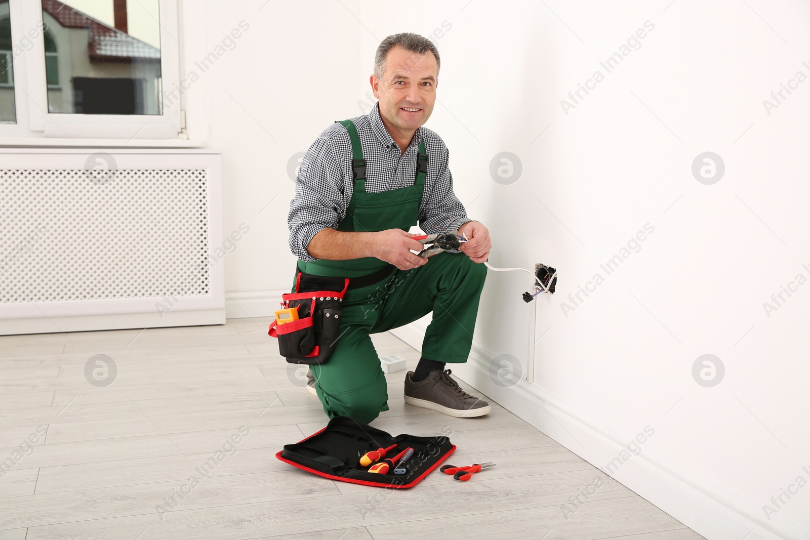 Photo of Professional electrician stripping wire ends with cutter indoors