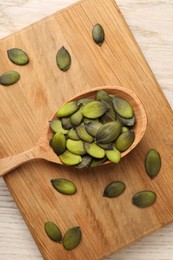 Photo of Spoon with pumpkin seeds on wooden table, top view