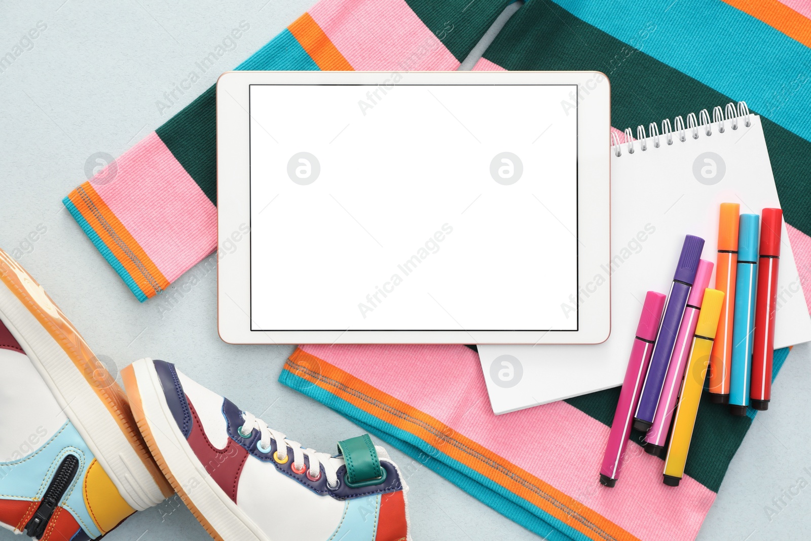 Photo of Modern tablet, clothes and stationery on light background, flat lay. Space for text