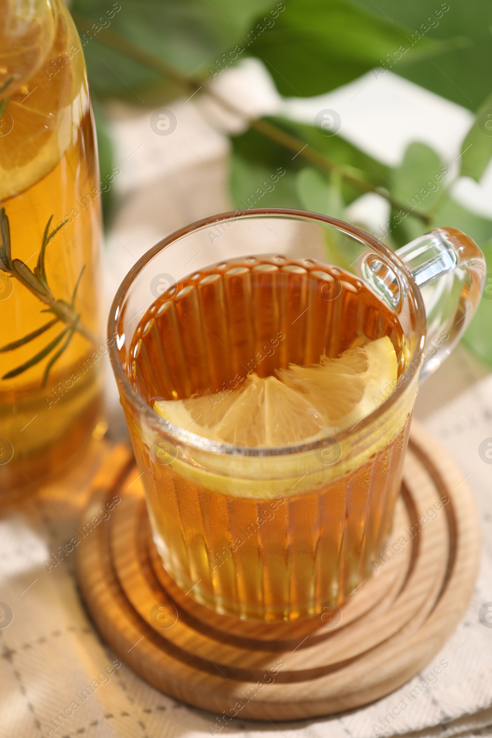 Photo of Glass cup of tasty iced tea with lemon on table, closeup