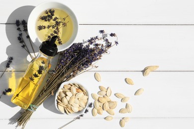 Photo of Healthy cooking oil, lavender flowers and pumpkin seeds on white wooden table, flat lay. Space for text