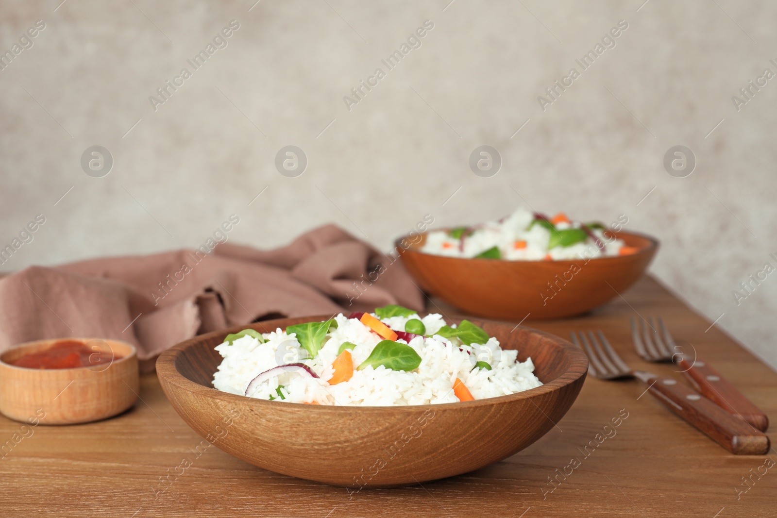 Photo of Bowl of boiled rice with vegetables on table