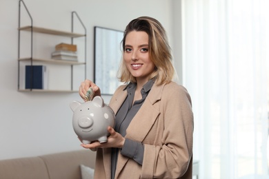 Photo of Businesswoman putting money into piggy bank indoors