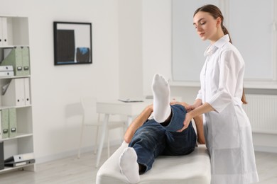 Professional orthopedist examining patient's leg in clinic