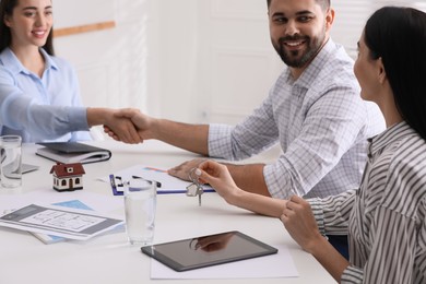 Photo of Real estate agent shaking hands with client in office, closeup. Mortgage concept
