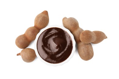 Photo of Bowl of tasty tamarind sauce and fresh pods isolated on white, top view