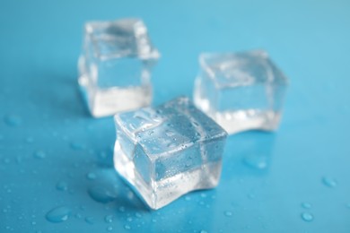 Photo of Ice cubes with water drops on light blue background, closeup