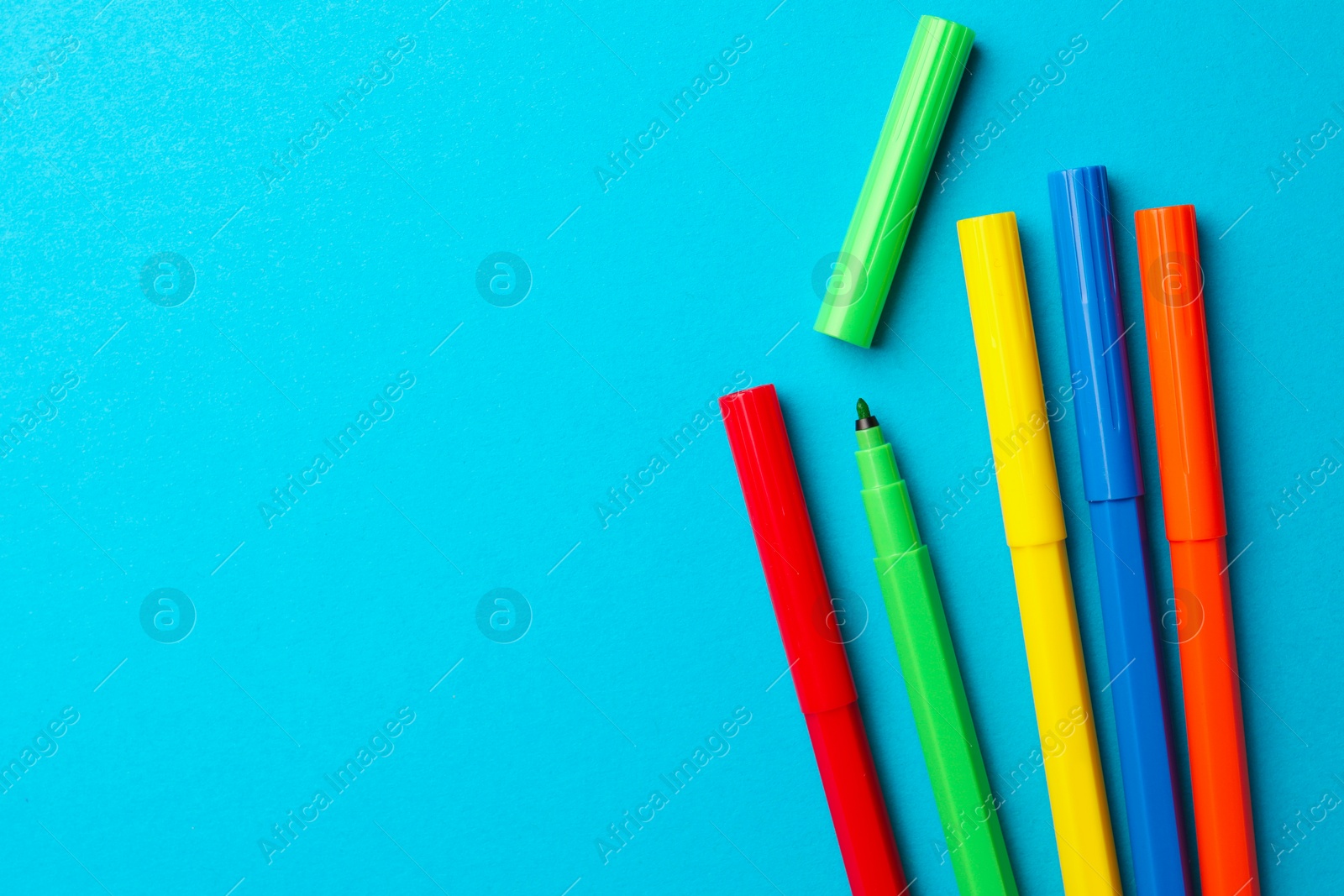 Photo of Many bright markers on light blue background, flat lay. Space for text