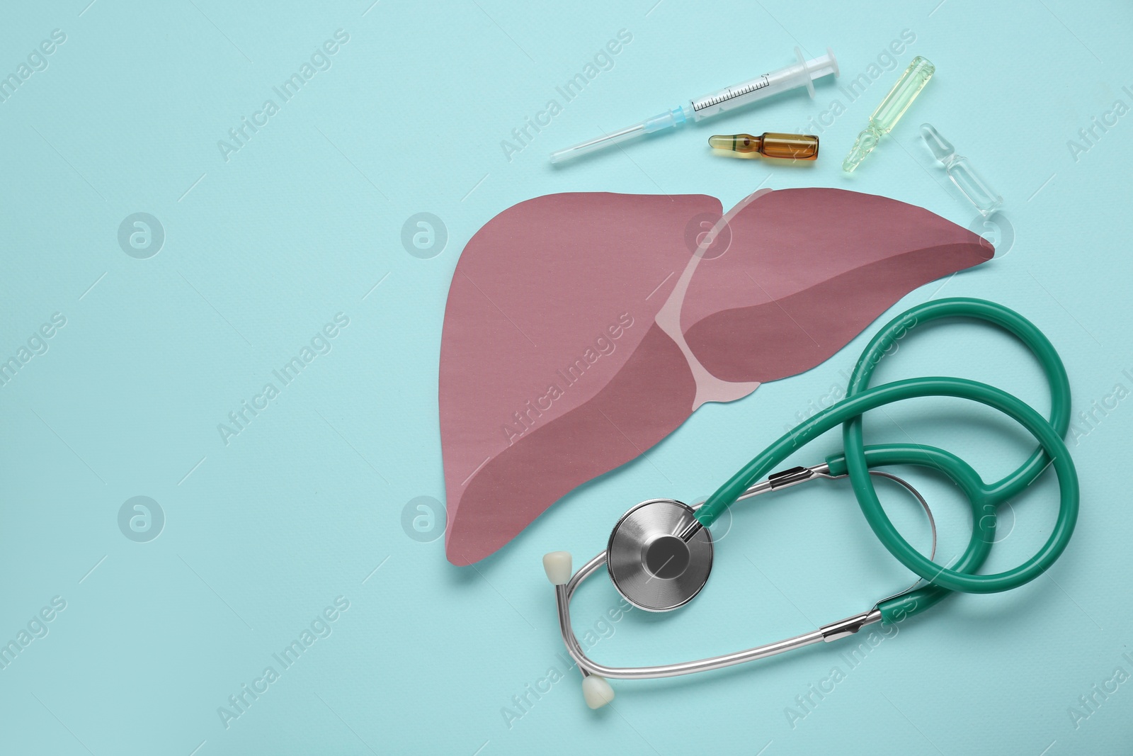 Photo of Paper liver, stethoscope, syringe and vials on turquoise background, flat lay with space for text. Hepatitis treatment