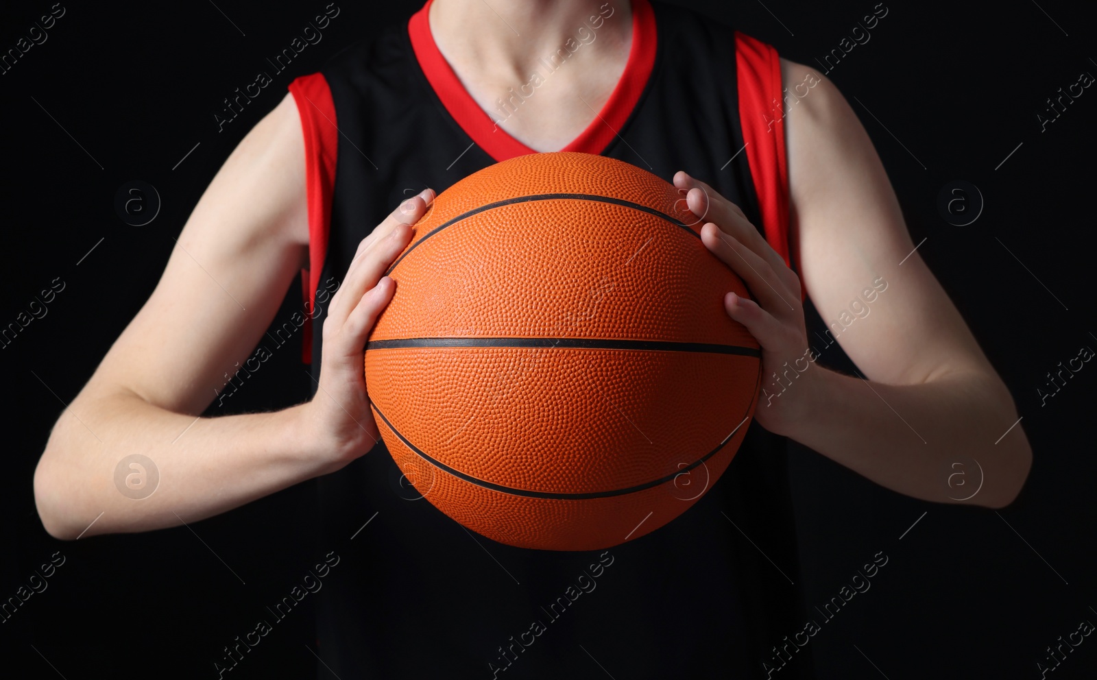 Photo of Boy with basketball ball on black background, closeup