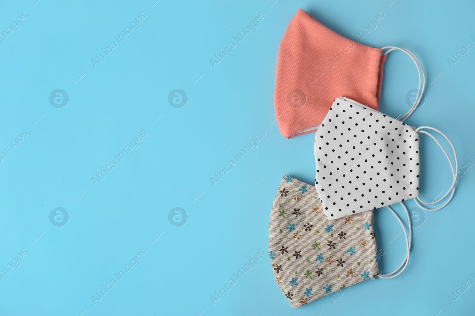 Photo of Homemade protective face masks on light blue background, flat lay. Space for text