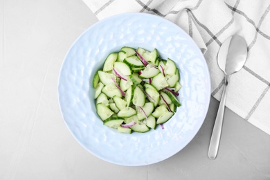 Plate of vegetarian salad with cucumber and onion served on table, flat lay