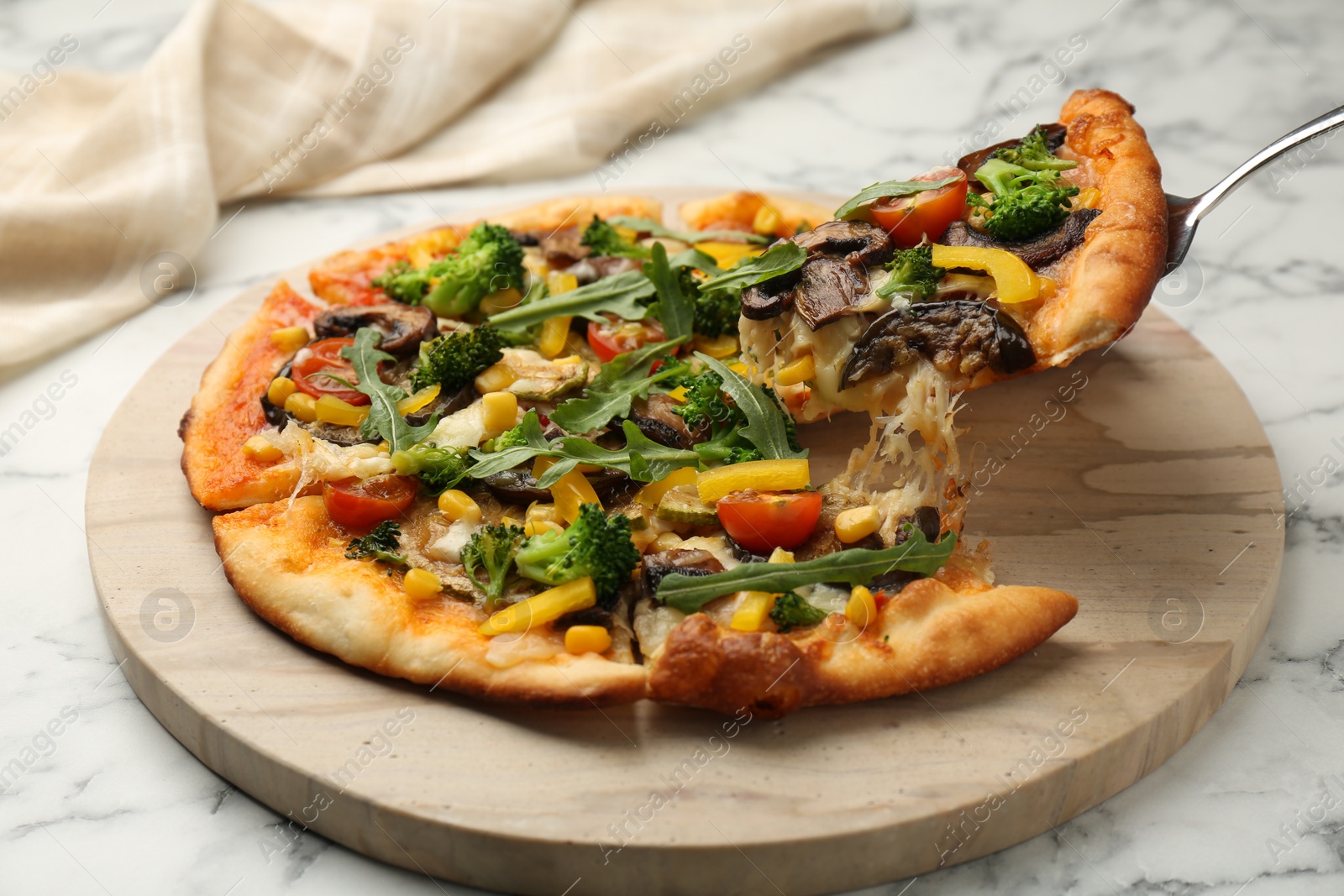 Photo of Taking piece of delicious vegetarian pizza at white marble table, closeup