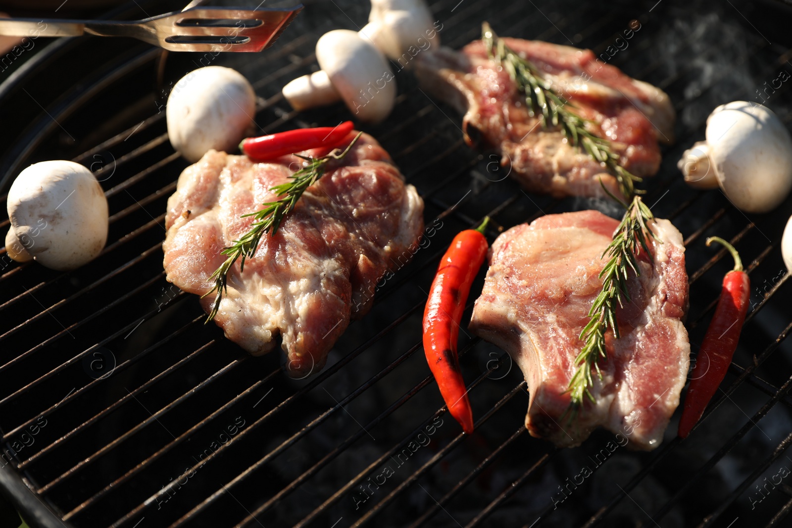 Photo of Cooking meat, chilli peppers and mushrooms on barbecue grill outdoors, closeup