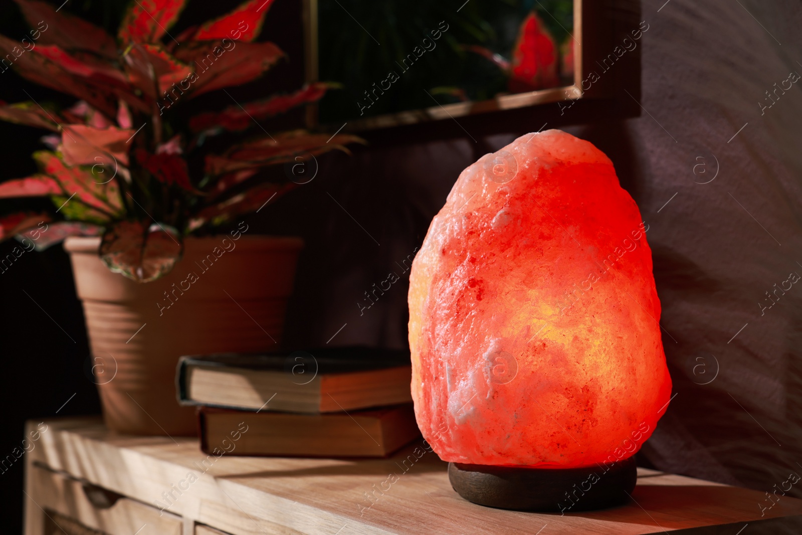 Photo of Himalayan salt lamp on wooden table near brown wall indoors